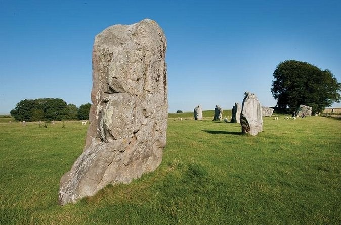 A standing stone with the great bank of the Avebury henge rising behind it